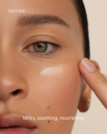 A close-up of a person applying a milky white cream under their eye with their fingertip. The gentle texture soothes and nourishes sensitive skin—perfect to complement an Ultra Calming Cleanser 300mL routine.