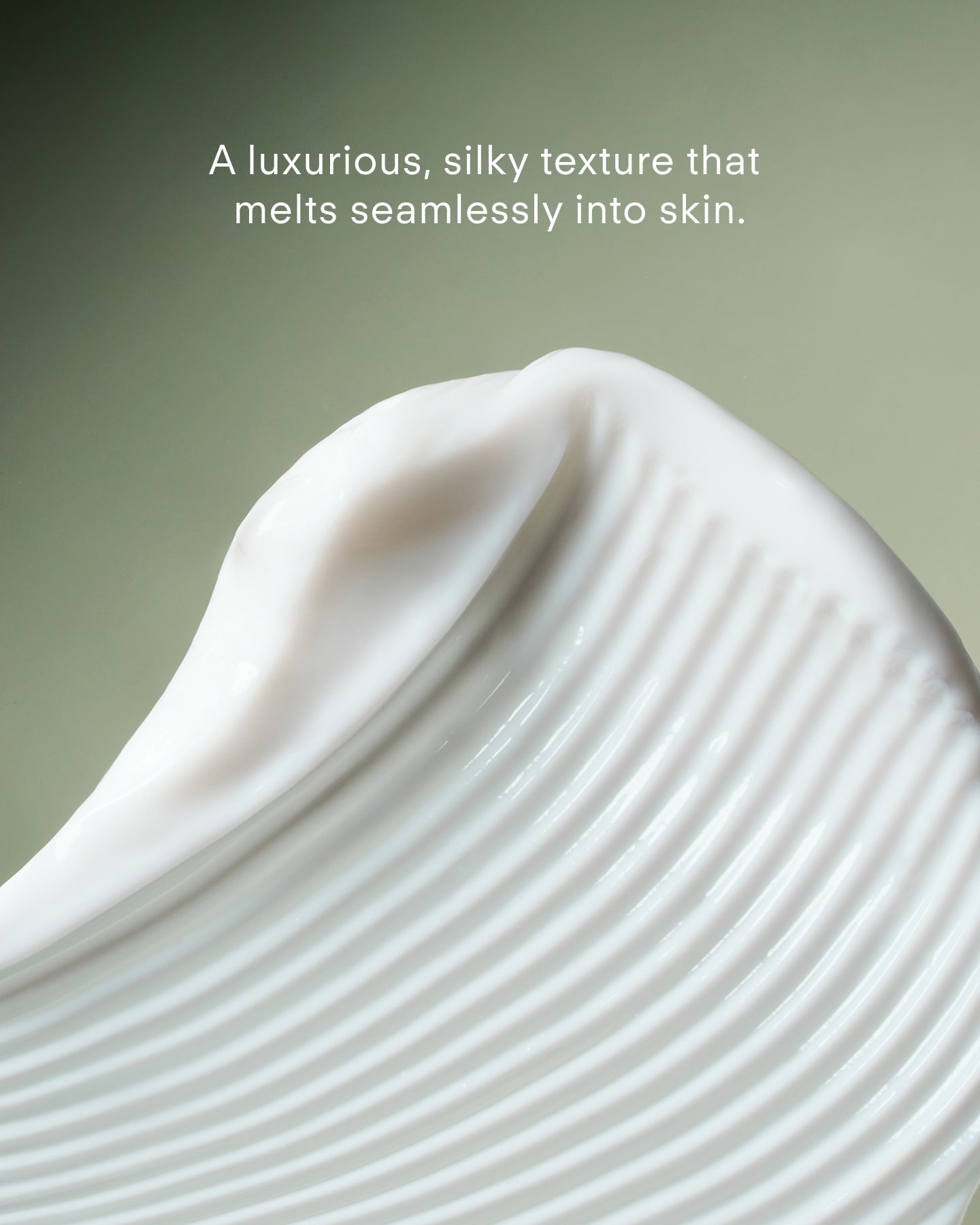 A close-up of Youth Boost ExoSignal GF² Facial Serum with creamy white, silky texture and smooth peaks on a soft green background. Text: Enhanced with Centella asiatica extract, this luxurious serum melts seamlessly into skin.