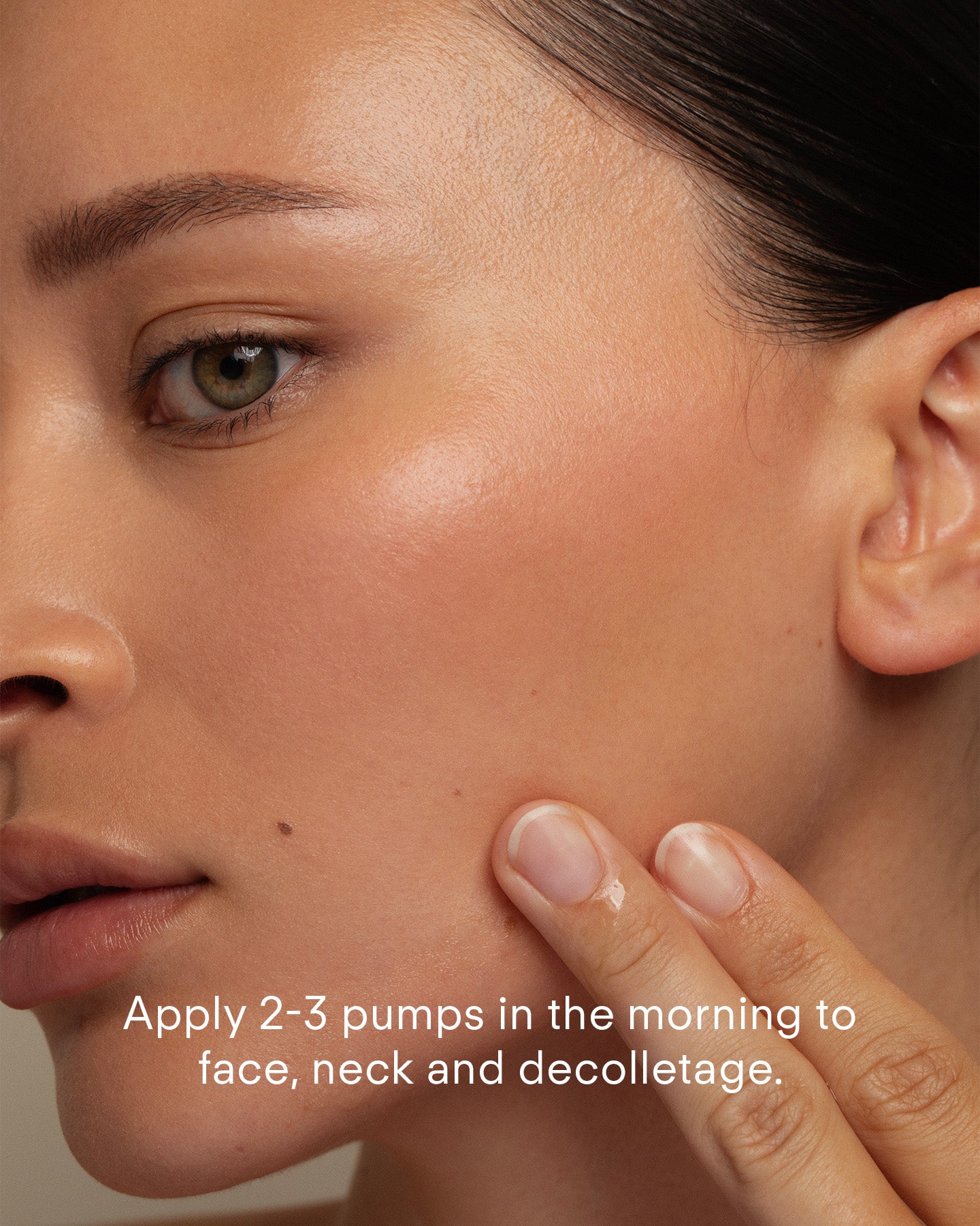 A close-up of a woman applying Ultra C Firming Concentrate to her cheek. The text reads: Use 2-3 pumps in the morning on face, neck, and decolletage to refine texture and brighten skin.