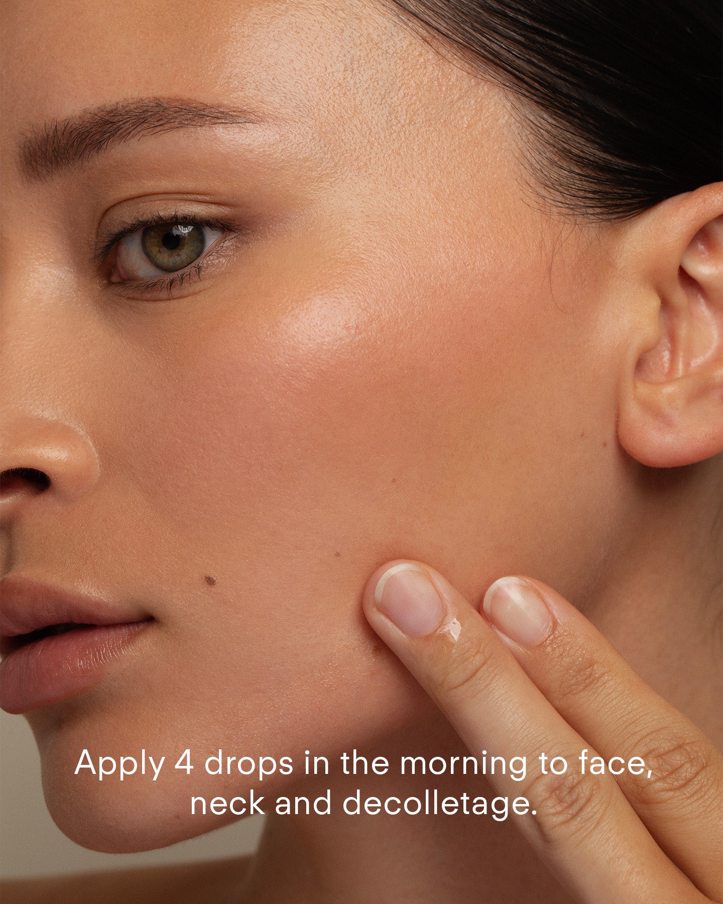 A close-up of a woman applying Ultra C+ Rejuvenating C Chebula Serum to her cheek. Text reads: Apply 4 drops in the morning to face, neck, and decolletage.