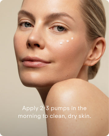 A woman with clear skin looks at the camera with three dots of cream under her eye. Text reads: “Apply 2-3 pumps of Youth Boost ExoSignal GF² Facial Serum Mini with plant-derived exosomes to clean, dry skin each morning.”.