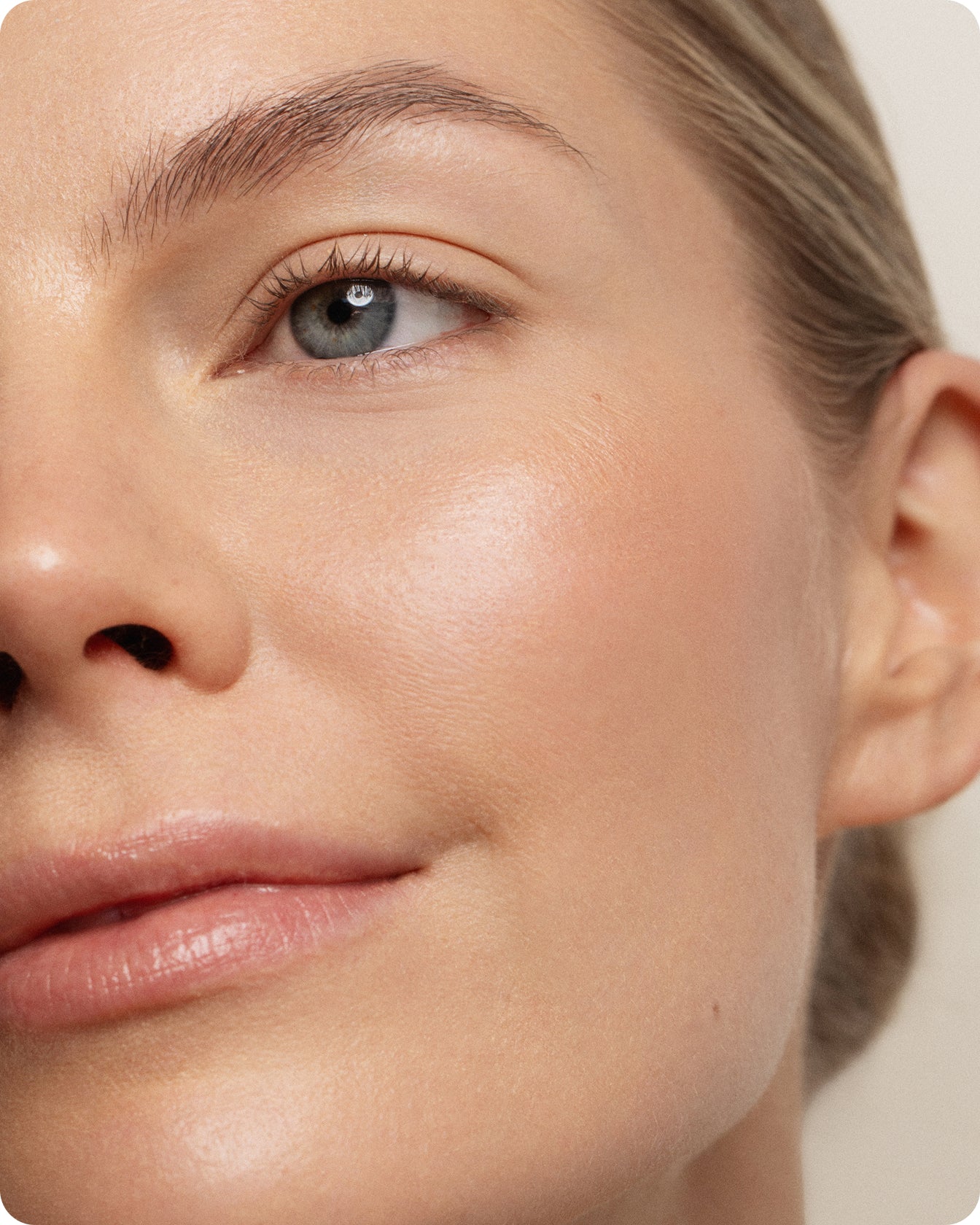 Close-up of a woman with clear skin, natural makeup, and blonde hair pulled back. Her glowing blue eyes and defined brows highlight the rejuvenating effects of Youth Boost ExoSignal GF² Facial Serum.