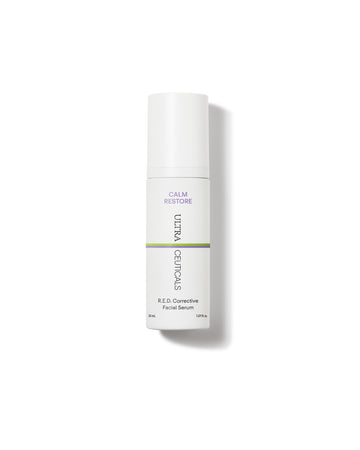A white bottle of Ultra R.E.D Corrective Serum for sensitive skin, with a pump dispenser and purple and green label text, stands upright against a white background.