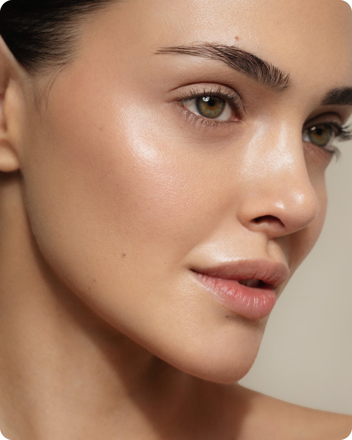Close-up of a person's smooth, glowing skin, green eyes, groomed brows, and natural makeup—showing a clear complexion and soft lips—thanks to Ultra R.E.D Corrective Serum that helps reduce redness and soothe stressed skin.