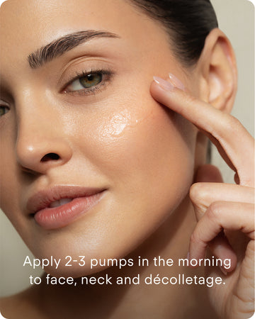 A woman applies B² Hydrating HA 360 Facial Serum Mini to her cheek with her finger. Text reads: “Apply 2-3 pumps in the morning to face, neck, and décolletage.”.