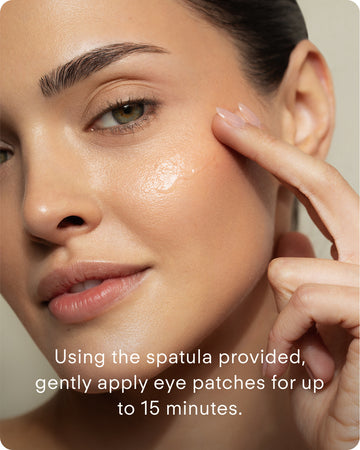 A woman uses the spatula to gently apply Ultra B² Hydrating Eye Mask patches with hyaluronic acid under her eyes for up to 15 minutes to target fine lines.