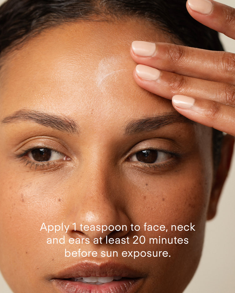 A person applies Ultra Retexturising Body Complex to their forehead with their fingers. Text reads: Apply 1 teaspoon to face, neck, and ears at least 20 minutes before sun exposure for effective UVA/UVB protection.